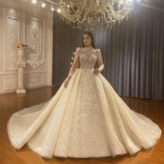 a woman in a wedding dress standing next to a chandelier with lights on it