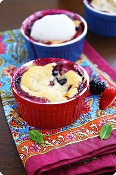 blueberry cobbler with ice cream and berries in red bowls on colorful napkins