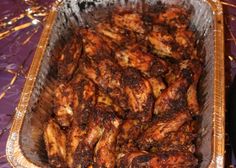 a pan filled with chicken wings sitting on top of a purple cloth covered tablecloth