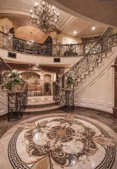 a large foyer with chandelier, marble floors and staircases that lead up to the second floor