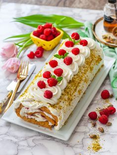 a cake with white frosting and raspberries is on a plate next to some flowers