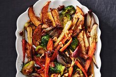 a white plate topped with carrots, broccoli and other vegetables