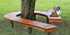 a wooden bench sitting next to a tree on top of a lush green park field