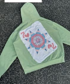 the back of a green hoodie with an embroidered design on it