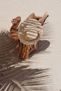 a woman laying on the beach in a hat