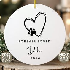 a white ornament with a dog's paw and heart on it that says forever loved duke