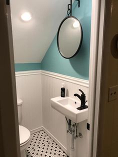 a white sink sitting under a bathroom mirror next to a black and white tiled floor