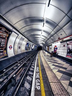 an underground subway station with people waiting for the train to come down it's tracks