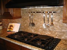 a stove top oven sitting inside of a kitchen next to wooden cabinets and counter tops