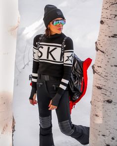 a woman standing next to a tree in the snow