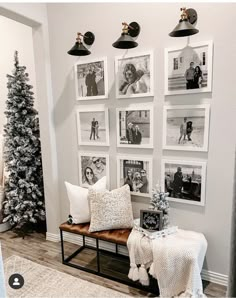 a living room with pictures on the wall and a bench in front of some christmas trees