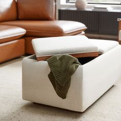 a white ottoman with a green sweater on it