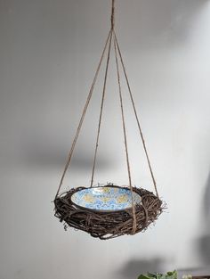 a bird's nest hanging from a rope with a blue plate in the middle