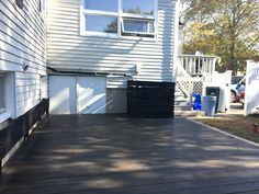 a house with a large wooden deck in front of it and two garage doors on each side