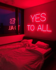 a bed in a room with red lights on the wall and a neon sign above it that says yes to all