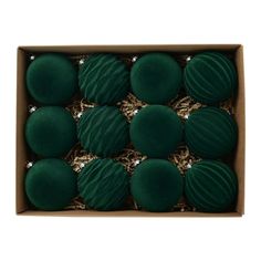 six green balls in a cardboard box on a white background with gold foil around the edges