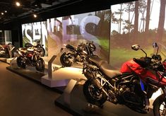 several motorcycles are on display in front of a large screen with the words s2