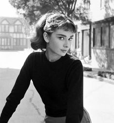 an old black and white photo of a woman on a bicycle