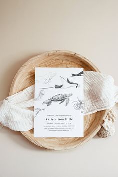 the wedding stationery is laid out on top of a wooden bowl with white yarn