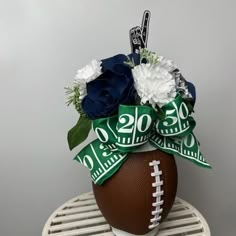 a football vase with flowers and ribbon tied around it