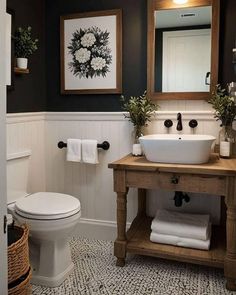 a white toilet sitting next to a sink in a bathroom under two framed pictures on the wall