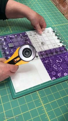 a person cutting fabric with a pair of scissors on top of it next to a piece of paper