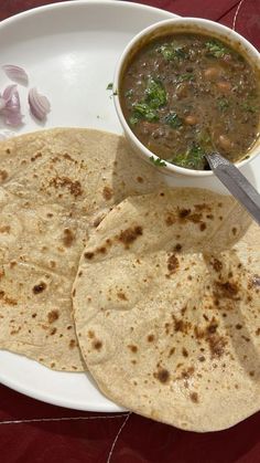 two tortillas on a plate with a bowl of soup