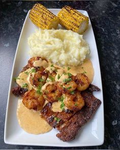 a white plate topped with meat, mashed potatoes and corn on the cob