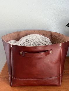 a brown leather tote bag sitting on top of a wooden table