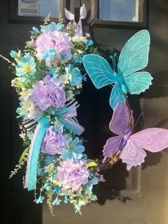 a wreath decorated with flowers and butterflies on the front door to a house or business