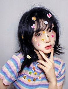 a girl with her hands on her face and some stickers all over her face