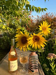 sunflowers and wine are sitting on an outdoor table