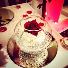 a glass vase filled with white and red flowers on top of a table next to a mirror