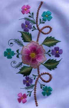 a close up of a flower on a white cloth with green and pink flowers in the center