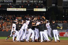 a group of baseball players huddle together on the field in front of an audience