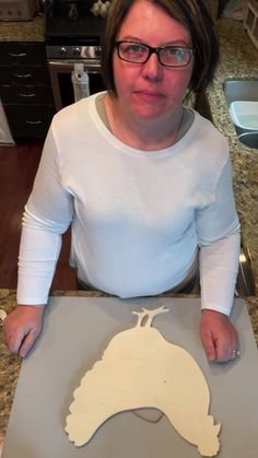 a woman sitting at a table with a cut out of a horse head on it