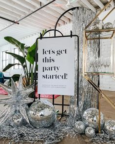 a sign that says let's get this party started next to some silver balls