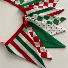 three red, white and green christmas ties on top of each other next to a pair of scissors