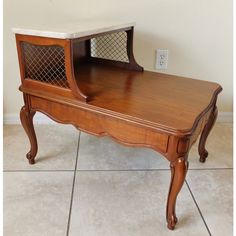 an old wooden desk with a glass door on the top and bottom shelf, sitting on tile flooring