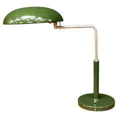 a green table lamp with a metal arm and shade on it's head, against a white background