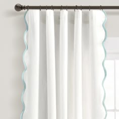 white curtains with blue scalloped trim hanging on a curtain rod