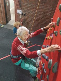 an older woman climbing up the side of a wall