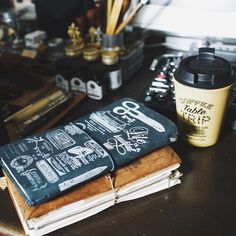 there is a coffee cup next to some books and pens on the desk with other office supplies