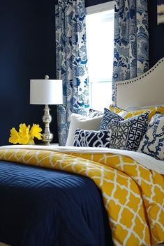 a blue and yellow bedroom with white bedding, pillows, and throw pillows on the bed