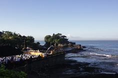 a group of people standing on top of a cliff next to the ocean