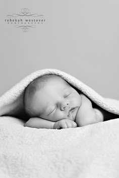 a black and white photo of a sleeping baby wrapped in a blanket with his eyes closed