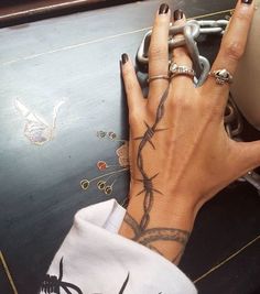 a woman's hand with barbed wire tattooed on her left wrist and the other hand holding a chain