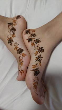 two feet covered in hendi tattoos on top of a white bedding sheet and pillows