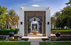 a white building with a fountain in front of it and palm trees around the entrance