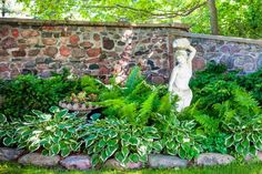 a stone wall with plants and a statue in the middle